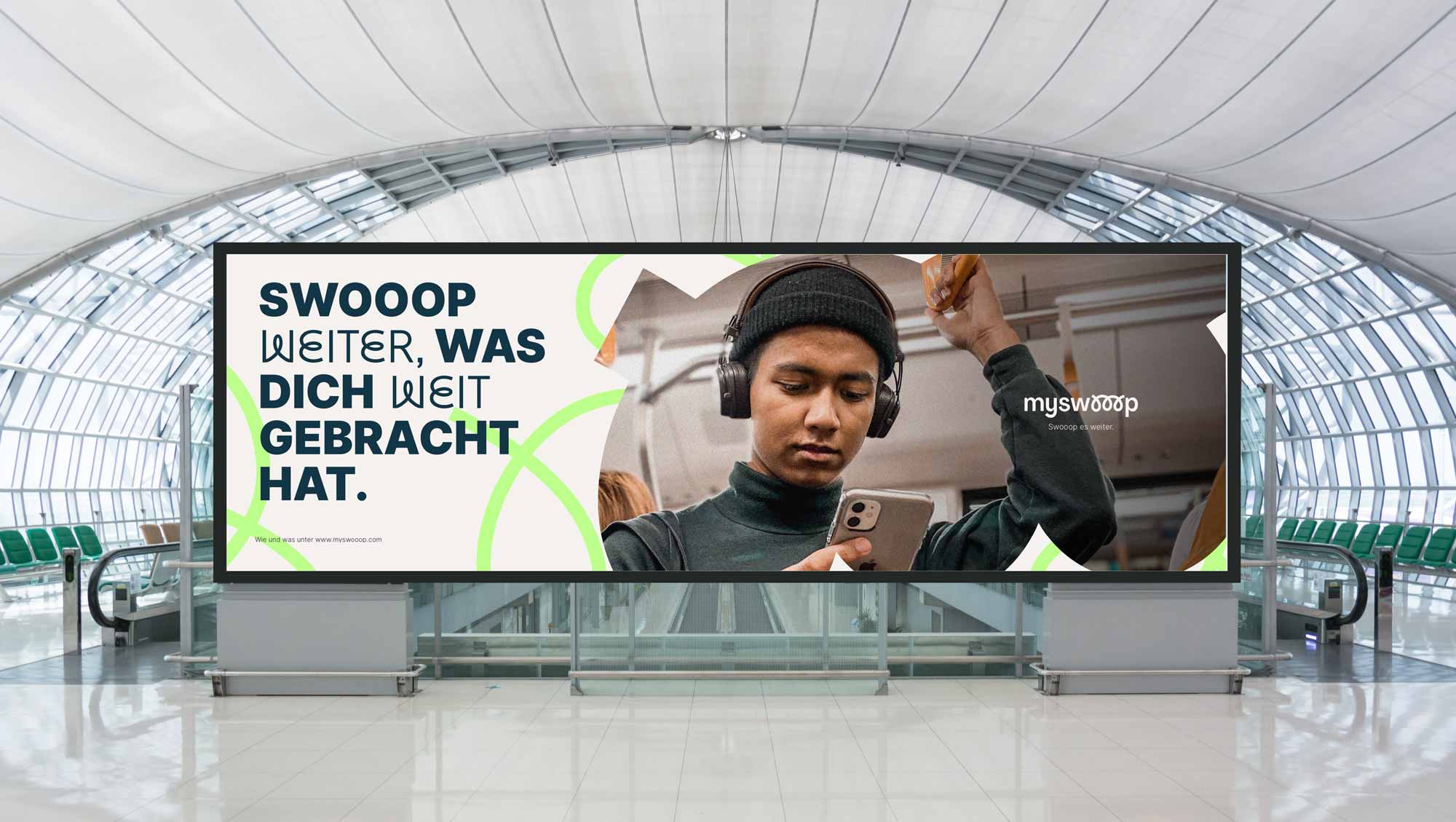 myswooop airport billboard — 'Swooop weiter, was dich weit gebracht hat.' with portrait of a young traveller using their phone