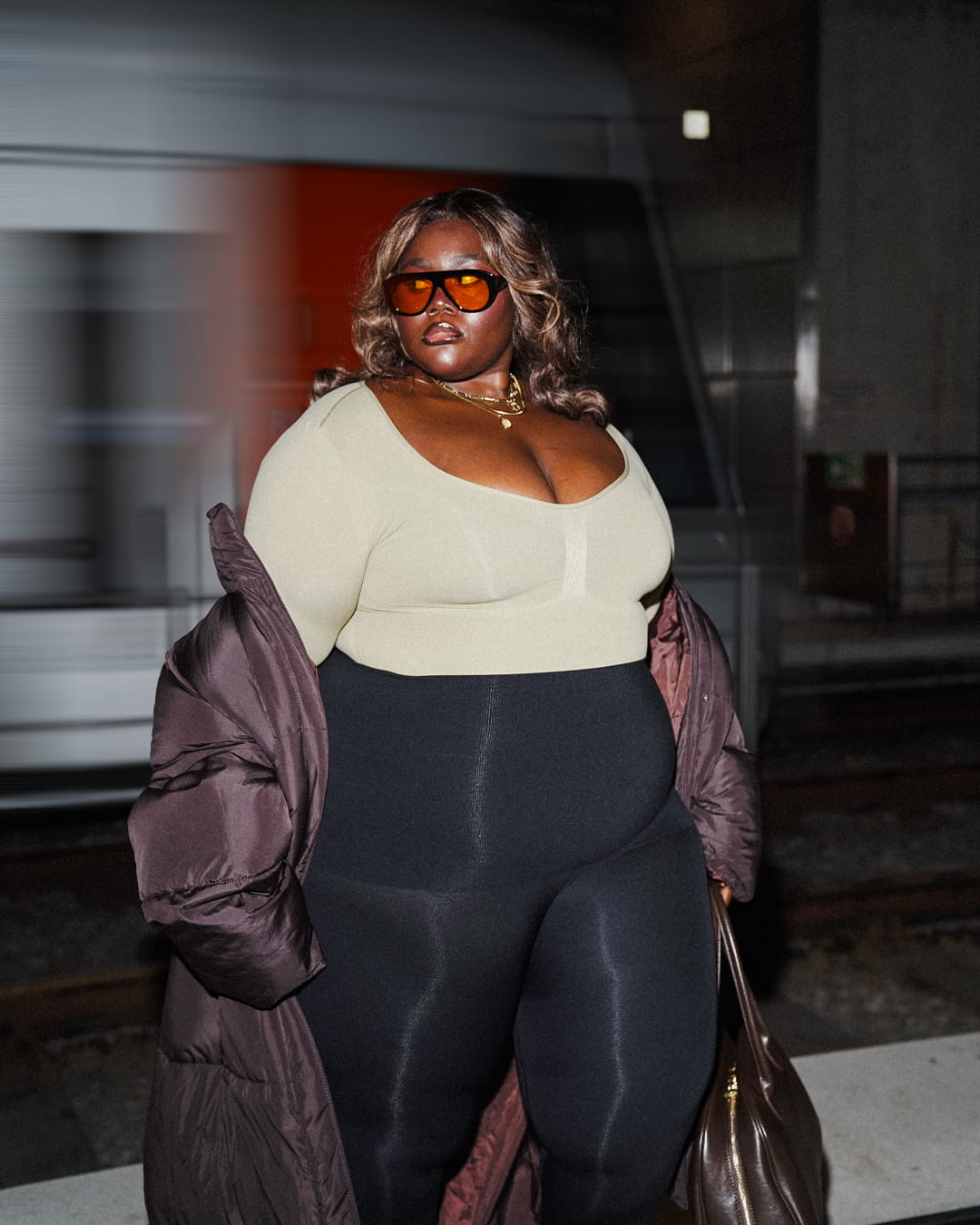 Richlove Rockson at a train platform at night, cream long-sleeve top with motion-blurred train behind
